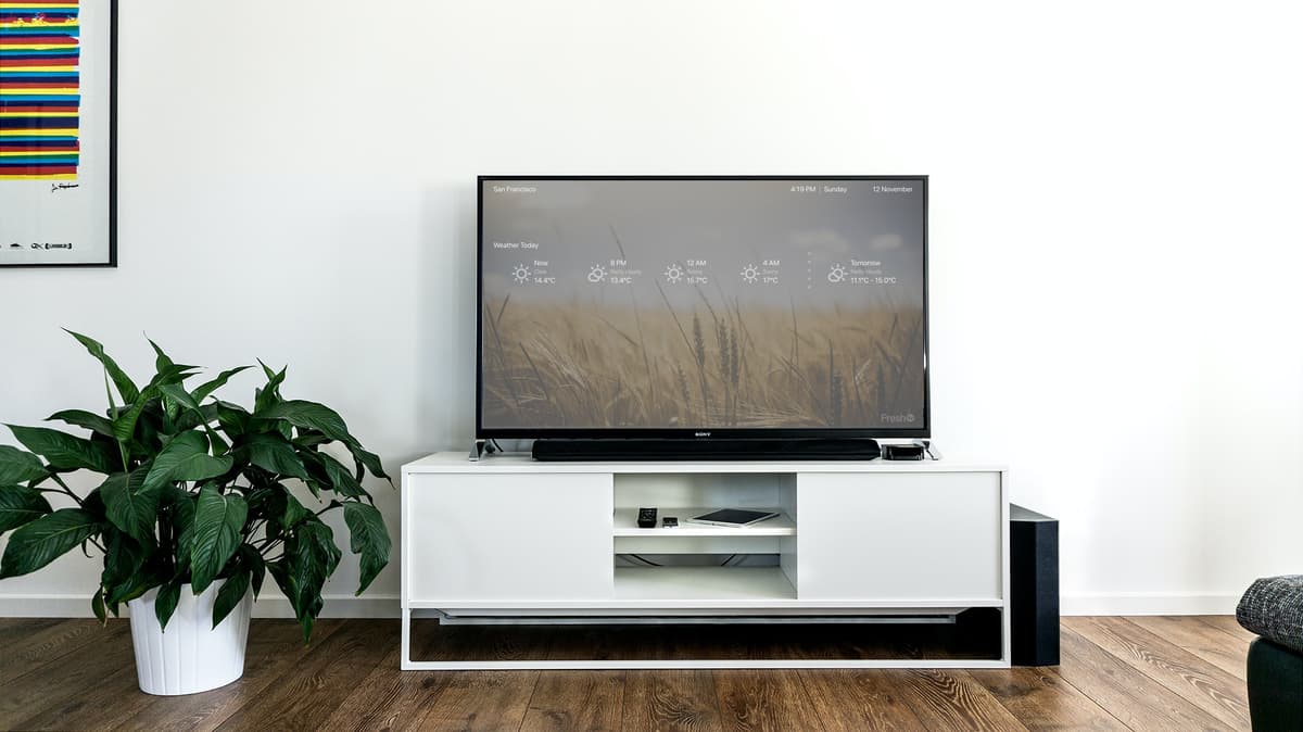 A FreshTV screen in a living room showing the weather over a wheat-field photo